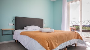 A bedroom with a bed, a bedside table, a power outlet, and a view of the outside balcony. - L'Atelier sur Seine (Epinay-sur-Seine)