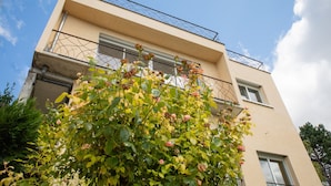 A two-story building with a balcony and a rose bush in the foreground. - L'Atelier sur Seine (Epinay-sur-Seine)