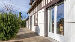 Eine Holzterrasse führt zu einem Haus mit großen Fenstern und einer Garagentür.