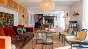 Ein geräumiges Wohnzimmer mit einer Couch, Sesseln, einem Couchtisch und einem Kamin.