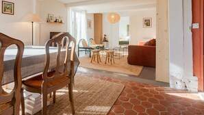 Ein modernes Wohnzimmer mit Essbereich, ausgestattet mit einem großen Fenster, einem Sofa, einem Couchtisch und einem Teppich.