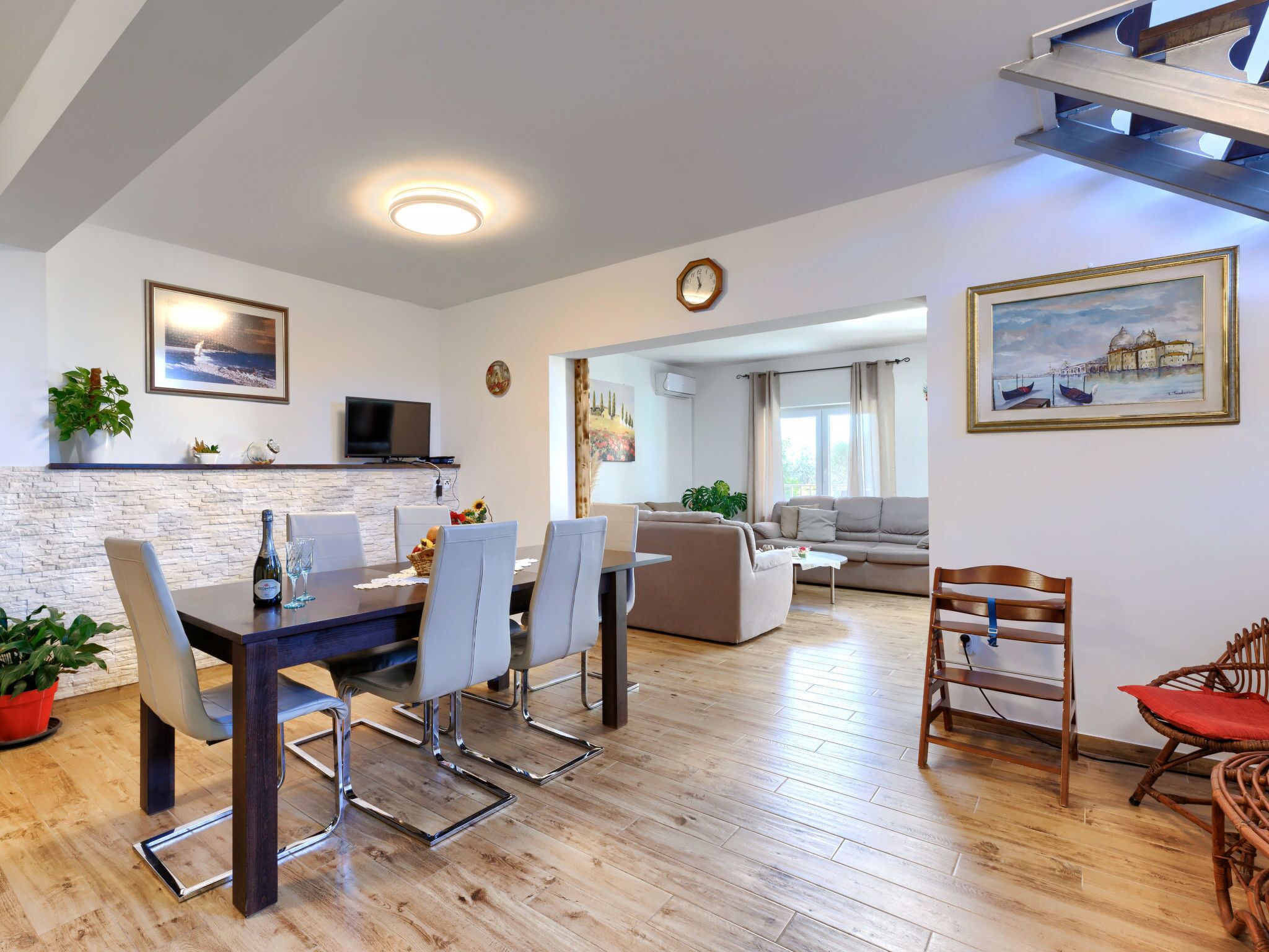 A modern living room with a dining area, a sofa set, and a wooden floor.