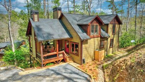 A cabin with a porch, a chimney, and a deck.