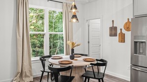 Une cuisine moderne avec une table de salle à manger ronde, des chaises noires et un réfrigérateur en acier inoxydable.