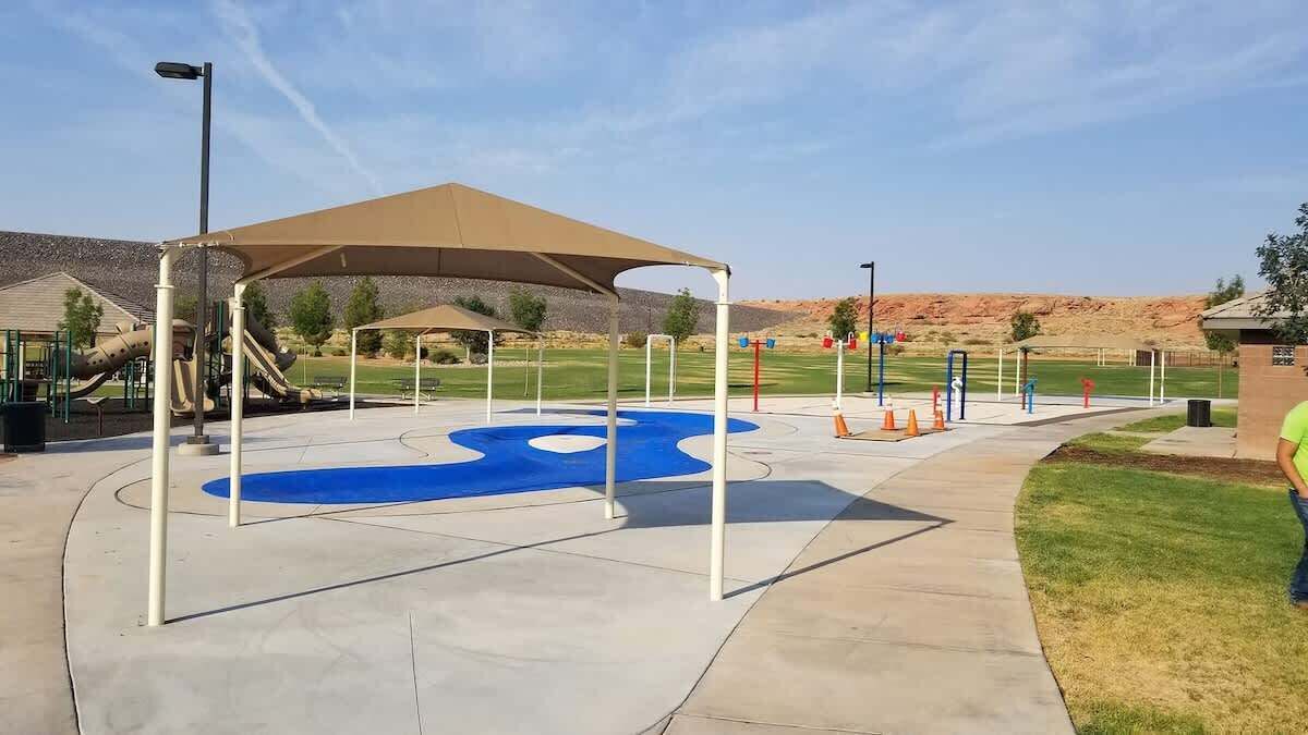 A playground with a slide, a blue circular play area, and a covered seating area.