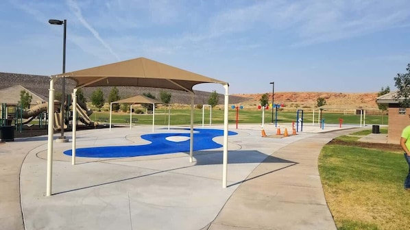 A playground with a slide, a blue circular play area, and a covered seating area.