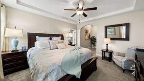 A bedroom with a large bed, a ceiling fan, a nightstand, a lamp, a chair, and a dresser. - A Dunes Oasis | Private Pool | Near Sand Hollow (Hurricane)