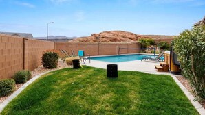 A backyard with a swimming pool, a brick wall, and a grassy area. - A Dunes Oasis | Private Pool | Near Sand Hollow (Hurricane)