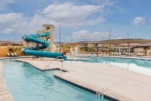 A swimming pool with a water slide, lounge chairs, and a building in the background. - Red Riviera | Prime Location For Adventure! (Washington)