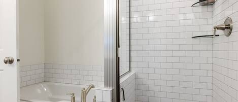 Un baño con bañera, cabina de ducha de cristal y pared de azulejos blancos.