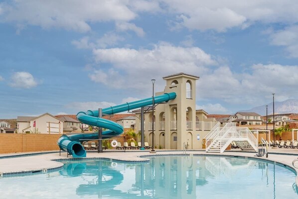 A swimming pool with a water slide, a building with a tower, and a clear sky. - Desert Riviera | Prime Location For Adventure! (Washington)