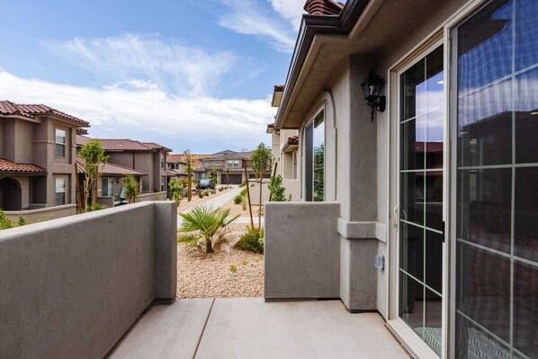 A residential building with a covered patio, a sliding glass door, and a view of neighboring houses. - Desert Riviera | Prime Location For Adventure! (Washington)
