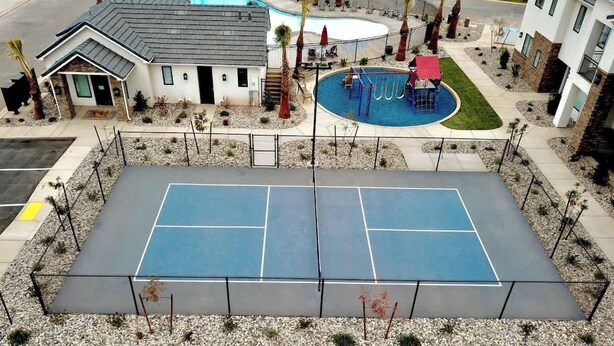Ein Tennisplatz mit Pool und einem Gebäude mit Satteldach.