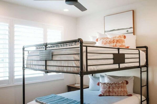 A bunk bed with a headboard, a bedside table, and a wall-mounted picture.