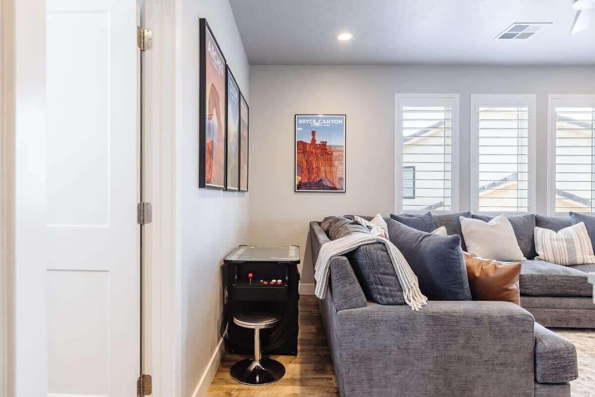 A living room with a grey sofa set, a small black table with a stool, and a poster of Bryce Canyon.