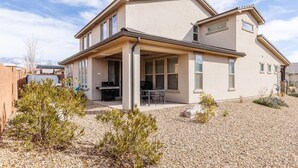 A two-story house with a covered patio, a small garden, and a gravel driveway.