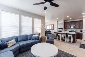 A modern living room with a sofa, a round coffee table, and a ceiling fan.