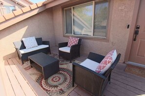 An outdoor patio with wicker furniture, a patterned rug, and a window.