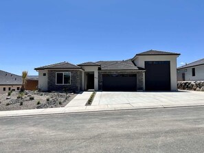 A modern two-story house with a garage, a stone facade, and a clear driveway.