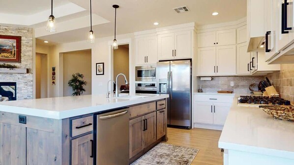 A modern kitchen with a central island, stainless steel appliances, and pendant lighting.