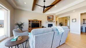 A spacious living room with a large sofa, a television, and a fireplace.