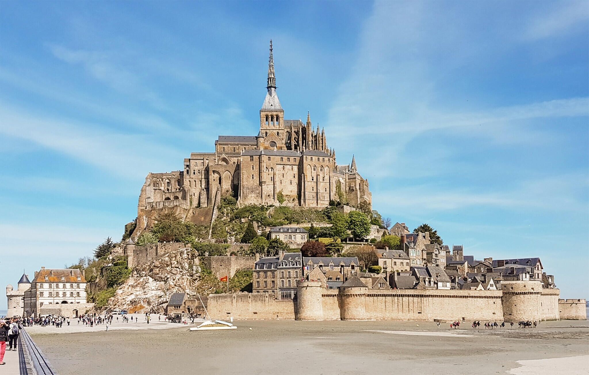 Eine historische Burg mit einem markanten Turm, gelegen auf einem Hügel mit Blick auf einen Strand.