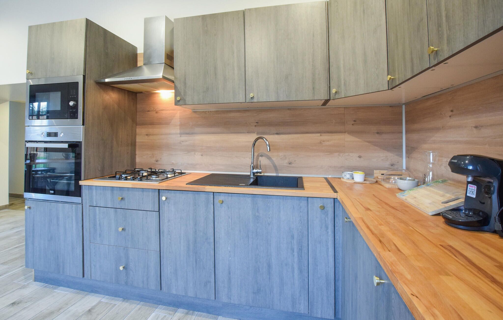 Una cocina moderna con electrodomésticos integrados, encimera de madera y un lavamanos.