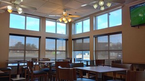 A spacious dining area with large windows, ceiling fans, and tables and chairs arranged for dining. - SAMIR Stay at NW Expressway (Oklahoma City)