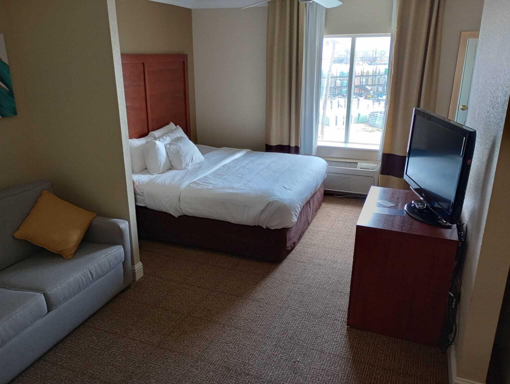 Ein Hotelzimmer mit Bett, Fernseher, Schreibtisch und einer Sitzecke.