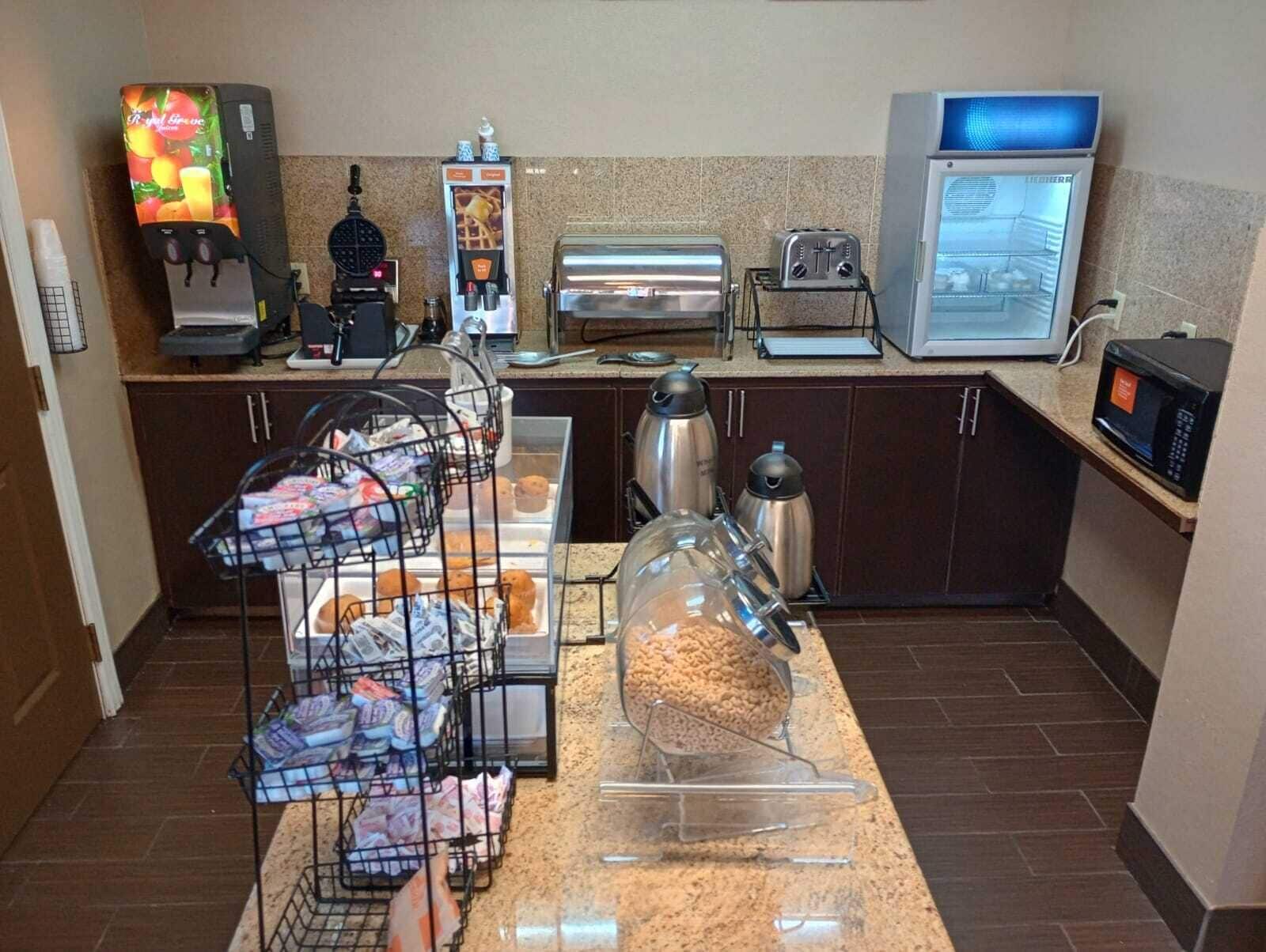 Une petite cuisine équipée d’une machine à café, d’un grille-pain, d’un four à micro-ondes et de divers récipients pour conserver les aliments.