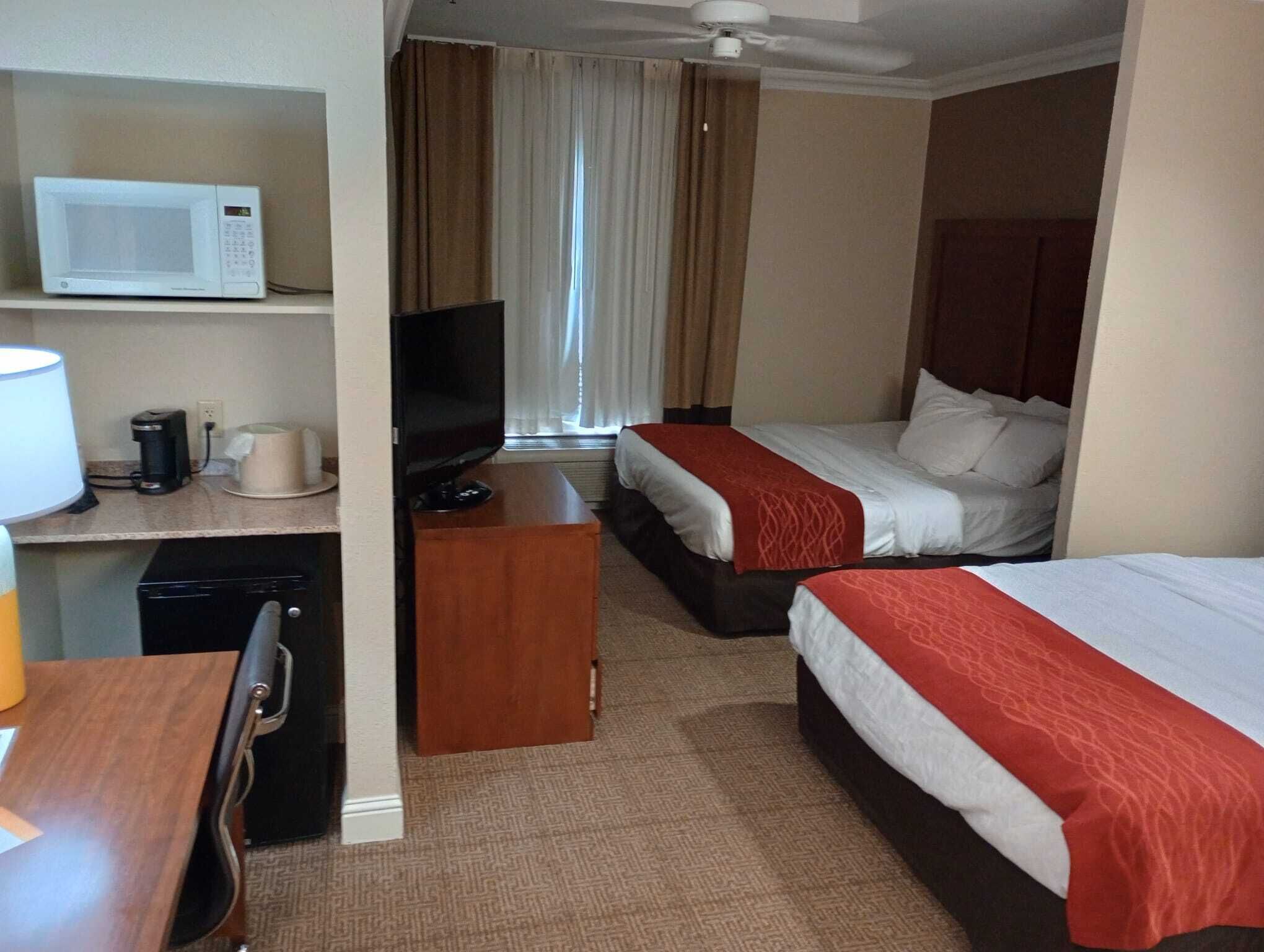 Una habitación de hotel con cama, televisión, microondas, cafetera y escritorio.