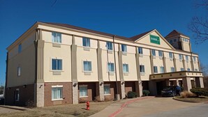 A multi-story hotel with a flat roof, a Samir Stay sign, and a parking area with a fire hydrant. - SAMIR Stay at NW Expressway (Oklahoma City)
