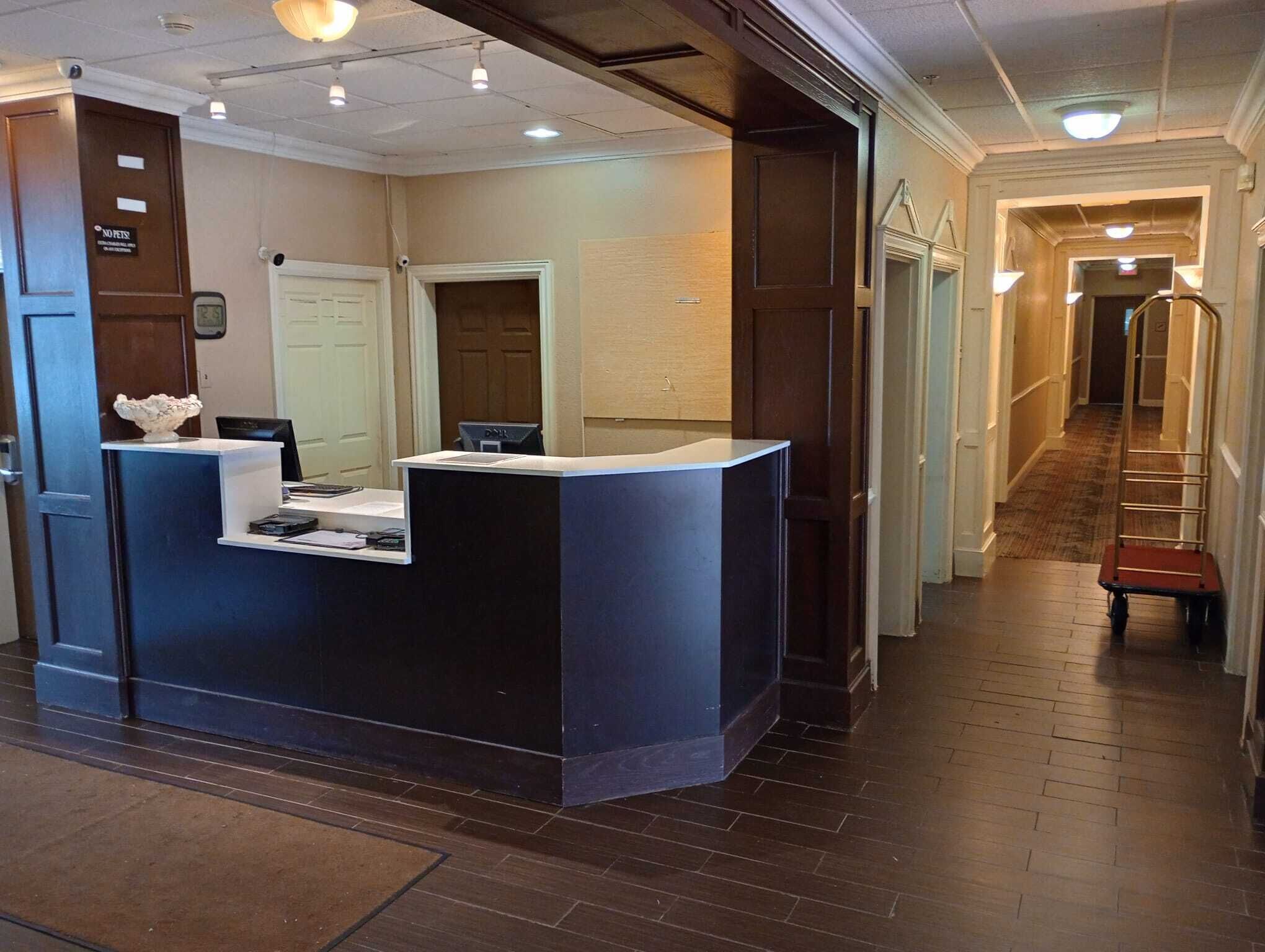 A reception desk with a computer, a small bowl, and a sign above it.