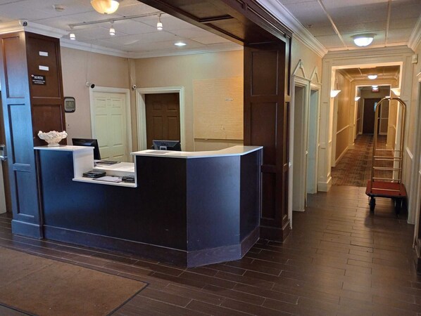 A reception desk with a computer, a small bowl, and a sign above it.