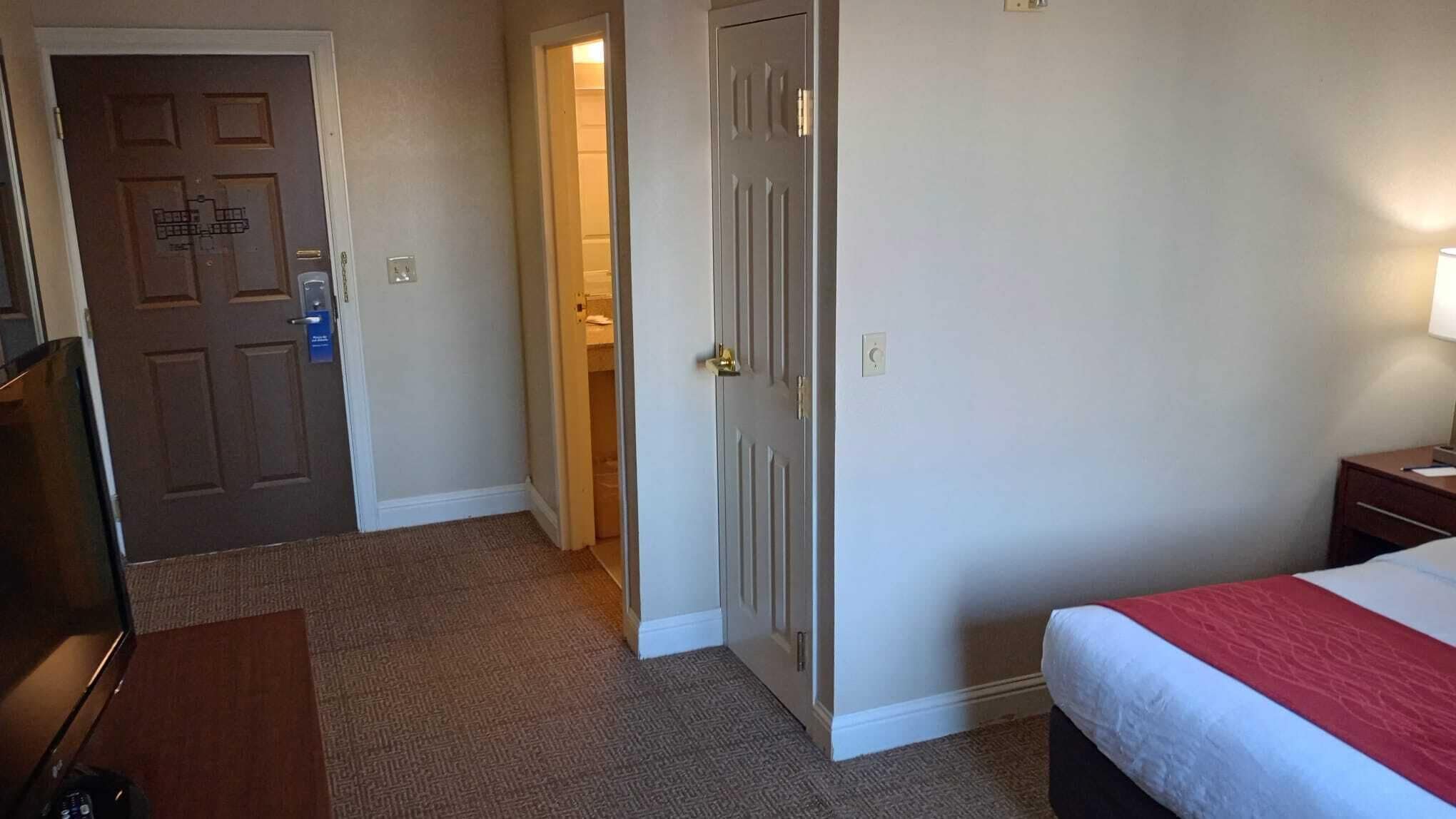 Une chambre d’hôtel comprenant un lit, un bureau, une chaise et une porte donnant accès à une salle de bain.