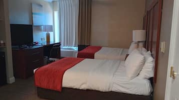 Een hotelkamer met twee bedden, een bureau en een stoel.