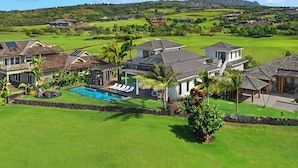 A golf course with houses, a swimming pool, and a view of mountains. - Spectacular View Home for 24!!Ocean, Mountain, golf views! 5min from Poipu beach (Koloa)