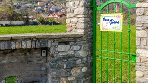 A stone wall with a green metal gate and a sign that reads "Casa Giove".