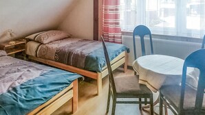 Ein kleines Zimmer mit zwei Holzbetten, einem Tisch und Stühlen.