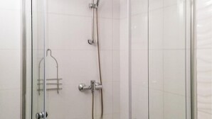 Eine Duschkabine mit Handbrause und am Wand montiertem Wasserhahn.