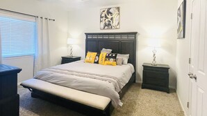 A bedroom with a bed, two bedside tables, a ceiling fan, and a window with blinds.