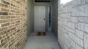 A narrow entrance with a white door, a small window above, and a concrete floor.