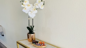 A marble console table with gold legs, a potted plant, and a tray of assorted candies.