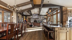 Une cuisine spacieuse avec des poutres en bois, un grand îlot central et un coin repas avec des chaises en bois.
