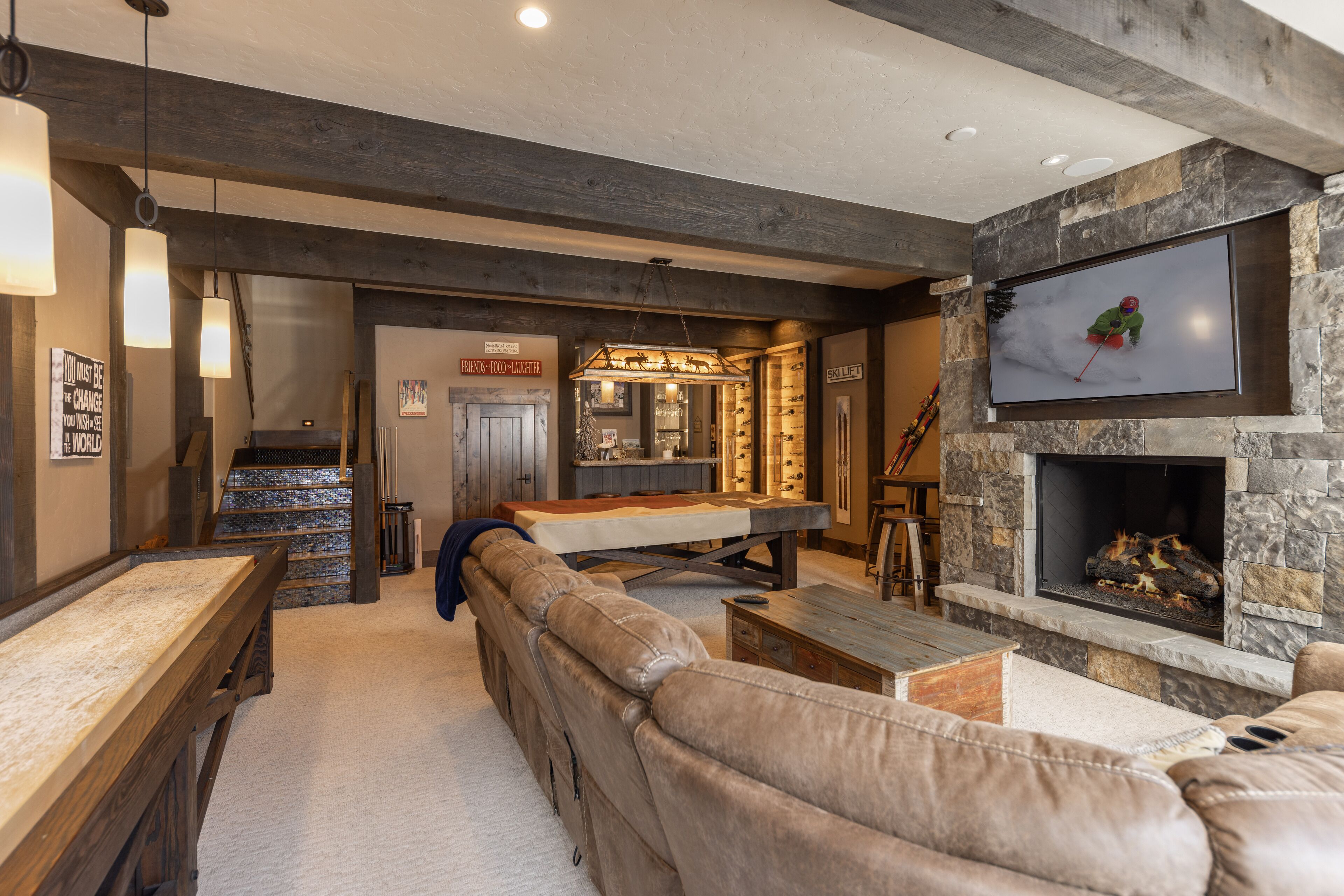 Una sala de estar acogedora con una mesa de billar, un sofá de cuero y una chimenea de piedra.
