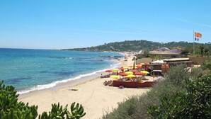A beach with umbrellas, a boat, and a flag. - Les Coteaux de la Nartelle by Interhome (Sainte Maxime)