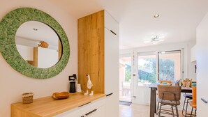 A modern kitchen with a wooden countertop, a round mirror with a green mosaic border, and a wooden panel above the cabinets. - Les Coteaux de la Nartelle by Interhome (Sainte Maxime)