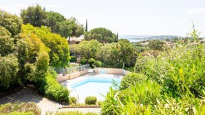 A pool surrounded by lush greenery and a view of the sea. - Les Coteaux de la Nartelle by Interhome (Sainte Maxime)