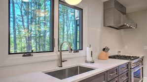 Una cocina moderna con un ventanal grande, electrodomésticos de acero inoxidable y una encimera blanca.