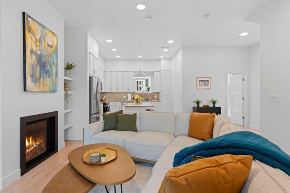 A modern living room with a fireplace, a sofa, and a dining table.